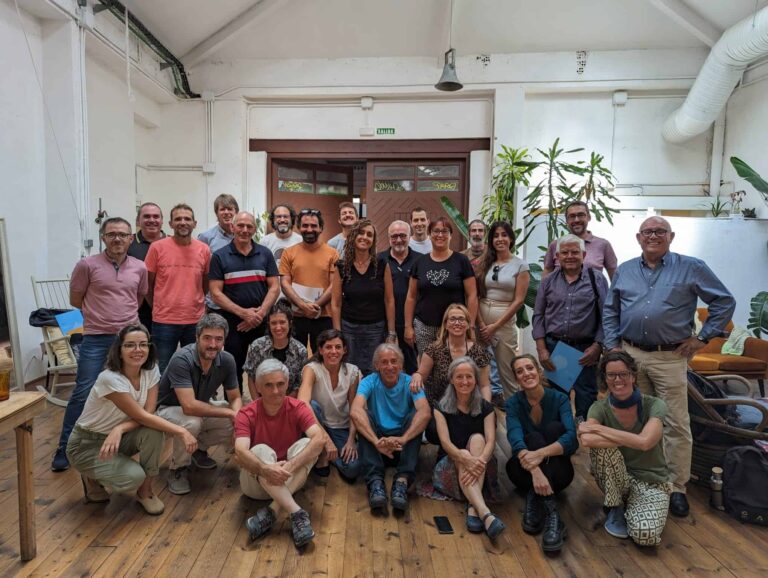 Imagen de las personas participantes en el primer encuentro de Sustentta en Madrid, localizados en una nave con el suelo de madera y plantas de fondo.